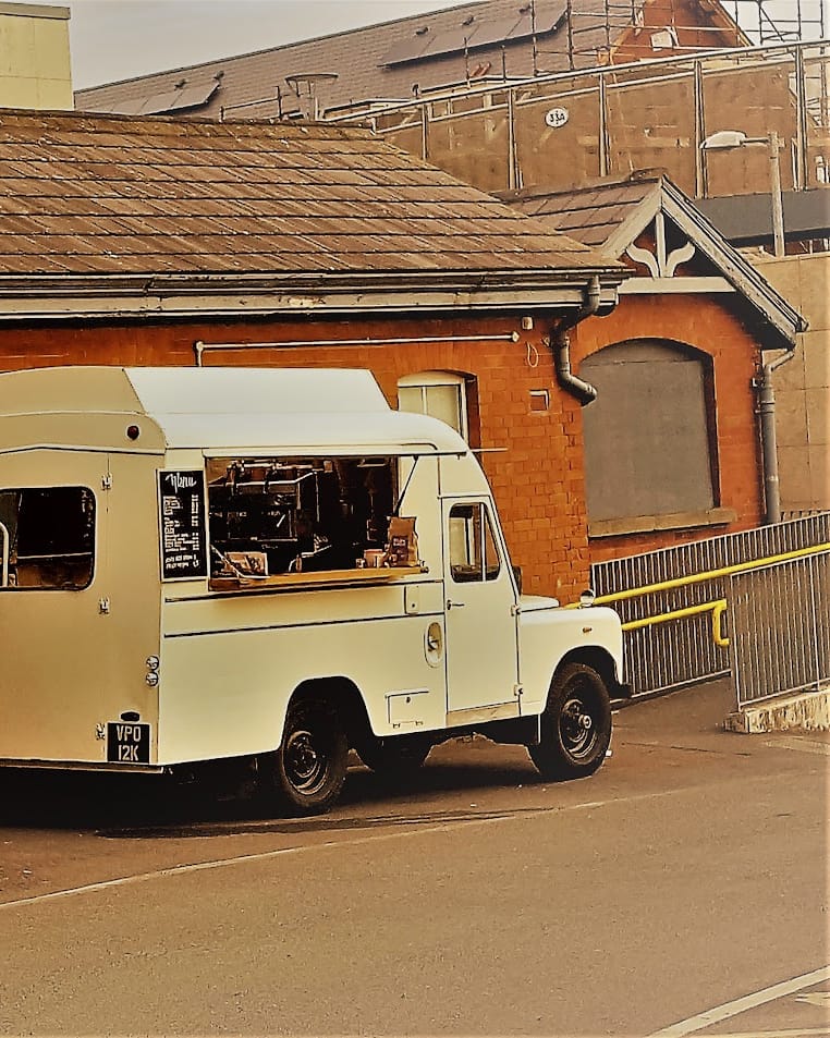 Cuppacabana's vintage Land Rover coffee van, parked beside a red-brick building