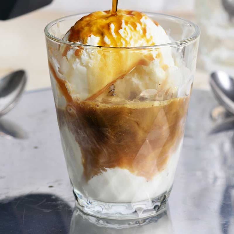 An affogato, vanilla ice cream with espresso poured over, served in a glass