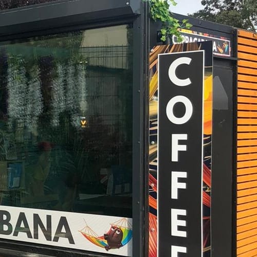 Close-up of the kiosk's vertical COFFEE sign board beside the CUPPACABANA shopfront lettering
