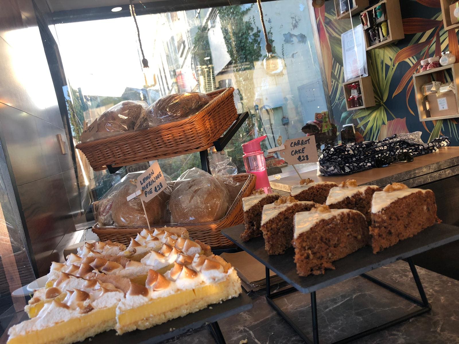 Bakery counter with bread baskets, lemon meringue pie and carrot cake, with hand-written price cards